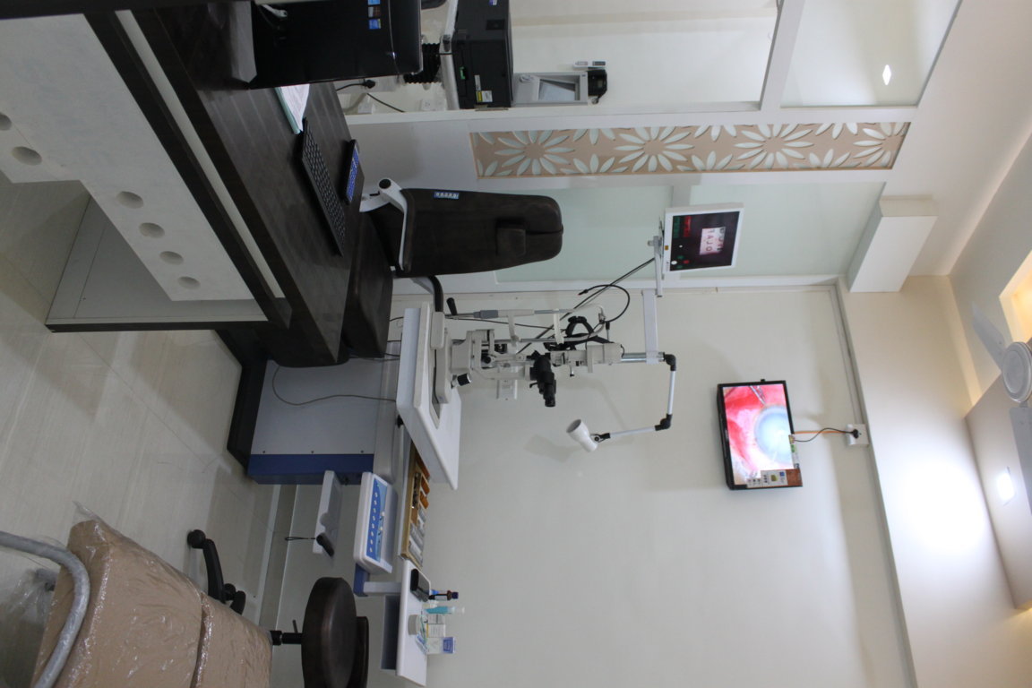 Refraction chamber at Insight Institute with a slit-lamp, trial-lens trays and a wall-mounted monitor streaming a live anterior-segment view